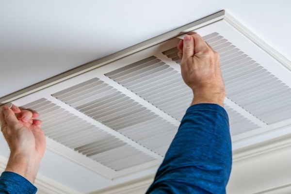 HVAC technician servicing an air vent in a Charlotte, NC home